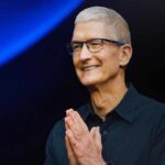CEO presenting at a technology event with hands clasped in a welcoming gesture