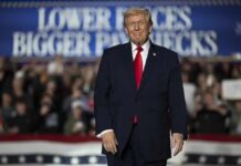 A speaker at a political rally smiling in front of a cheering crowd