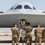 Military personnel inspecting a stealth bomber aircraft