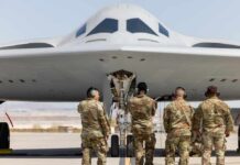 Military personnel inspecting a stealth bomber aircraft