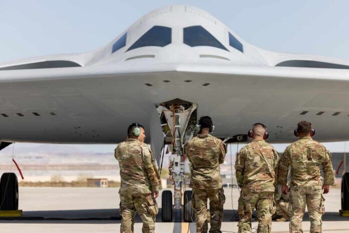 Military personnel inspecting a stealth bomber aircraft