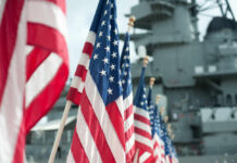 Row of American flags in front of a naval ship