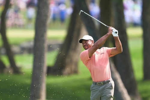 Golfer swinging club on green golf course