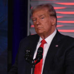 Shocking War Crime Claim: Trump Accused On-Air Man in suit at a microphone, red background.