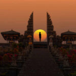 Silhouette between ancient temple gates at sunset.