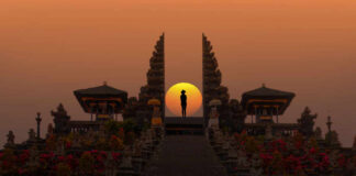 Silhouette between ancient temple gates at sunset.