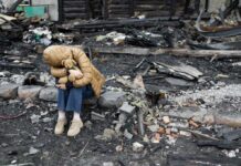 UN Report: Unseen Child War Victims Soar A child sitting on a stone amidst a devastated landscape, holding a teddy bear