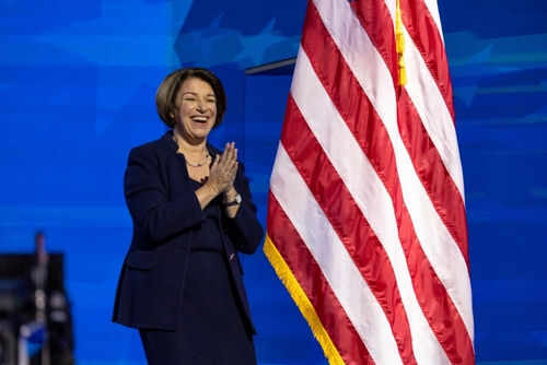 Person clapping near American flag on stage.