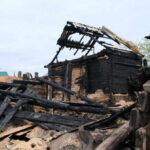 Unsolved Death: Is Arson Hiding the Truth? Burned wooden house with collapsed, charred beams and roof remains