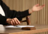 Judge's hand striking a wooden gavel on a block