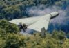 A kamikaze drone flying over a dense forest