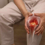 Person holding knee with highlighted joint pain illustration