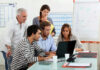 Five people working together in an office meeting.