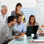 Five people working together in an office meeting.