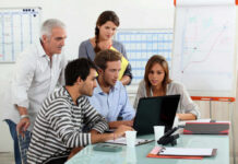 Five people working together in an office meeting.