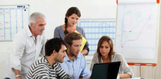 Five people working together in an office meeting.