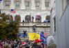 Crowd with flags gathered outside a neoclassical government building