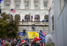 Dems Go Nuclear: Block Trump Payouts! Crowd with flags gathered outside a neoclassical government building