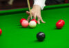 Shocking Sacrifice: Snooker Star’s Family Tale A hand preparing to strike a cue ball on a snooker table