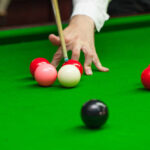 A hand preparing to strike a cue ball on a snooker table