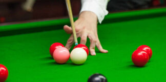 A hand preparing to strike a cue ball on a snooker table