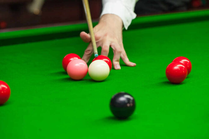 A hand preparing to strike a cue ball on a snooker table