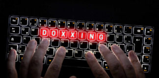 Hands typing on a backlit keyboard with the word 'DOXXING' illuminated in red