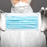 Medical professional holding a blue surgical mask
