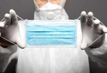 Medical professional holding a blue surgical mask