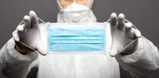Medical professional holding a blue surgical mask