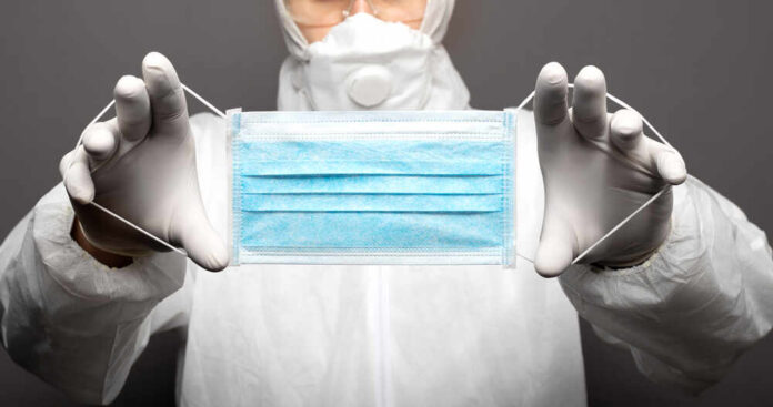 Medical professional holding a blue surgical mask