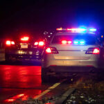 Police car with flashing lights parked on the roadside at night