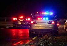Police car with flashing lights parked on the roadside at night