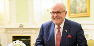 A smiling man in a striped suit standing in an elegantly decorated room