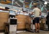 Customers using self-checkout machines in a grocery store