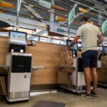 Self-Checkout Chaos: Theft Skyrockets! Customers using self-checkout machines in a grocery store