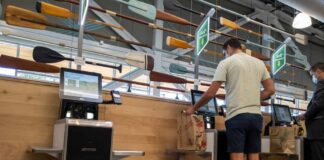 Customers using self-checkout machines in a grocery store