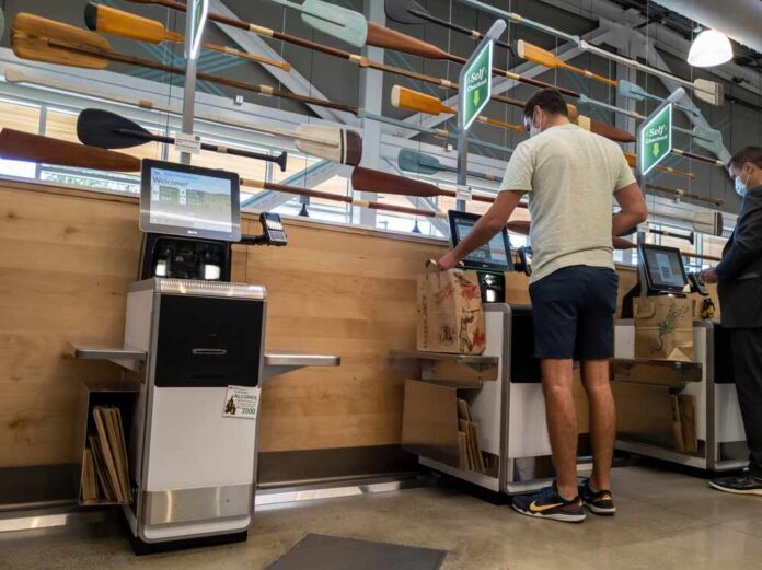 Customers using self-checkout machines in a grocery store