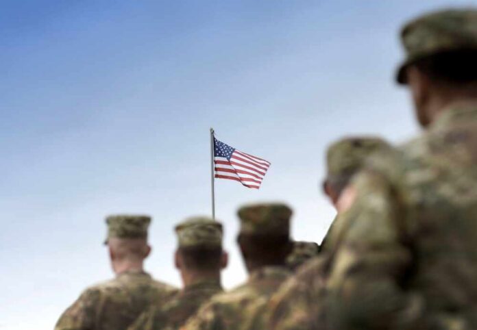 shutterstock_2380883205.jpg Soldiers standing in formation with an American flag in the background