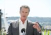 A man in a suit speaking at a press conference outdoors