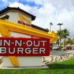 In-N-Out Burger restaurant sign with a bright yellow arrow