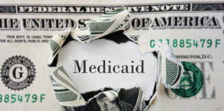 A torn dollar bill revealing the word 'Medicaid'