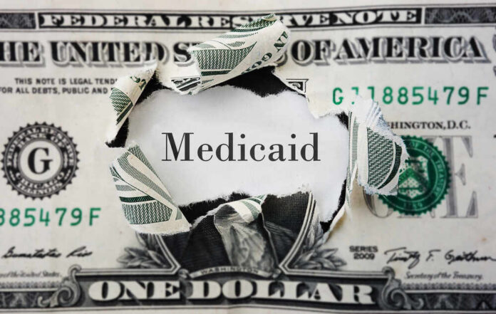 A torn dollar bill revealing the word 'Medicaid'