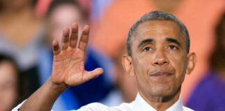 A speaker gesturing with one hand while addressing an audience