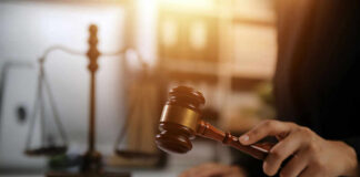 Judge's hand holding a wooden gavel above a sound block