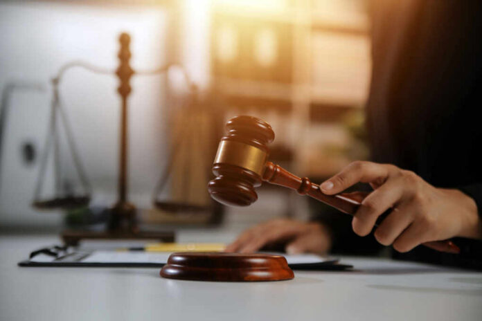 Judge's hand holding a wooden gavel above a sound block