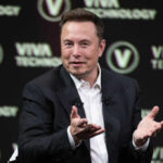 Trillionaire Label Sparks Clash Over Wealth Taxes Man in a suit speaking on stage with hand gestures