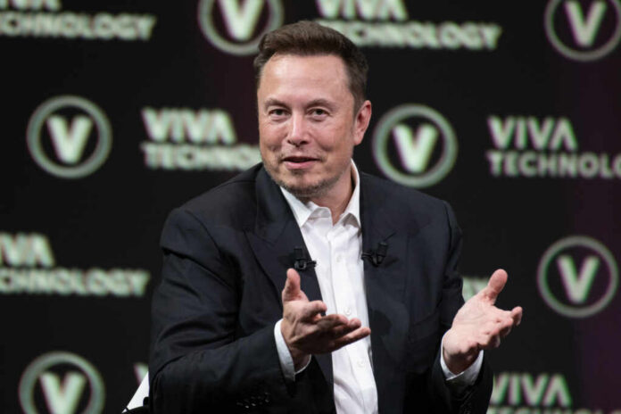 elon-musk2318800317jpg Man in a suit speaking on stage with hand gestures