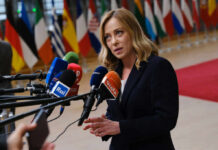 Trump Torches Meloni—Italy Blinks On Iran Woman speaking at a press conference with multiple microphones