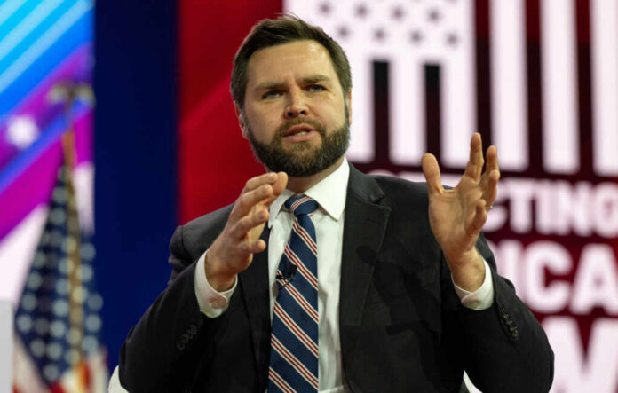 Man in suit speaking on stage with gesturing hands